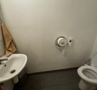 Mosdó mosdókagylóval és csempével. Üzlethelyiség egyszerű berendezéssel.