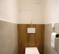Fürdőszoba egy kétszobás lakásban fa dekor padlóval és WC-vel.