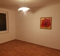 Szoba egy háromszobás lakásban, fa dekor padlóval és rózsa festménnyel.