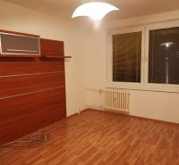 Szoba fa dekoros padlóval, fehér falakkal és fali szekrénnyel egy háromszobás lakásban.