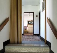 Folyosó egy családi házban faajtókkal és csempézett lépcsőkkel.