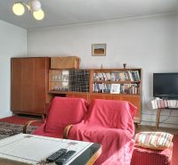 Nappali egy családi házban szőnyegekkel, fotelekkel és televízióval.