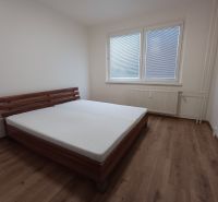 Hálószoba ággyal és fa dekorációjú padlóval egy háromszobás lakásban.