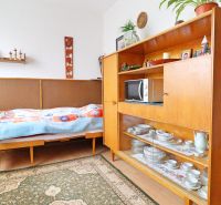 Szoba családi házban ággyal, retro bútorokkal és porcelánnal teli polcokkal.