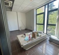 Irodák nagy ablakokkal, légkondicionálóval és rendetlenséggel, fa dekorációjú padlóval.