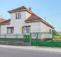 Családi ház Borsky Mikulášban fehér falakkal és zöld kerítéssel.