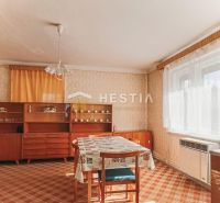 Családi ház belső tere étkezőasztallal, régebbi bútorokkal és szőnyeggel.