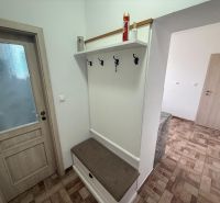 Előszoba egy kétszobás lakásban fogasokkal és fa dekorációjú padlóval.