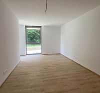Tágas szoba egy üdülő apartmanban fehér falakkal és fa dekorációjú padlóval.