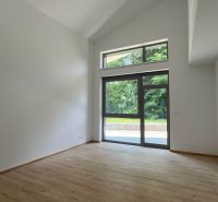Nyaraló apartman belső tere nagy ablakkal és fa dekorációjú padlóval.