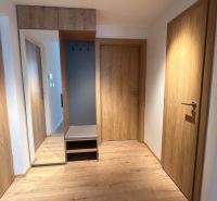 Nyaraló apartman belső tere fa dekorációjú padlóval és nagy tükörrel ellátott beépített szekrénnyel.
