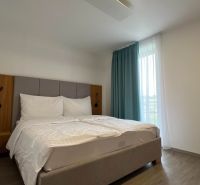 Rekreációs apartman kényelmes ággyal, függönyökkel és fa dekorációjú padlóval.