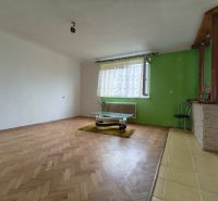 Nappali szoba fa mintázatú padlóval és zöld fallal egy háromszobás lakásban.