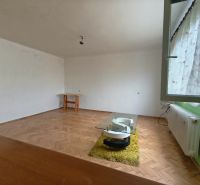 Nappali egy háromszobás lakásban, fa dekorációjú padlóval és bútorokkal.