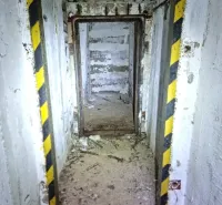 Elhagyatott belső tér egy különös ingatlanban betonfalakkal és poros padlóval.