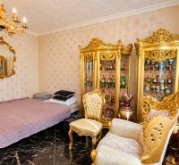Luxusos berendezés aranyozott bútorokkal, csillárral és tükörrel az egyszobás lakásban.