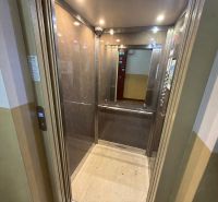 Felújított lift fa dekorációval a falakon egy 3 szobás lakásban.