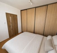A háromszobás lakás hálószobájának belső tere fa dekorációjú padlóval és nagy szekrénnyel.
