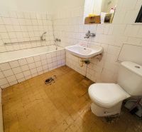 Fürdőszoba egy kétszobás lakásban káddal, mosdóval és WC-vel, fehér csempével burkolva.