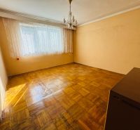 Szoba egy kétszobás lakásban kristálycsillárral és fa dekorációjú padlóval.