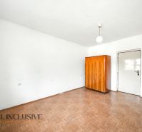 Egy családi ház szobája fehér falakkal, fa mintázatú padlóval és fa szekrénnyel.