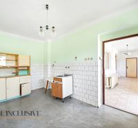 Konyha egy családi házban egyszerű konyhabútorral, fehér csempékkel és szürke padlóval.