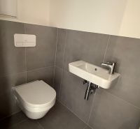 Kis fürdőszoba háromszobás lakásban WC-vel és mosdóval.