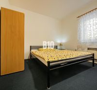 Hálószoba családi házban fém ággyal, szekrénnyel és mintás függönnyel.