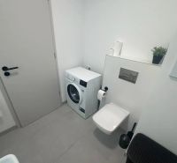 Fürdőszoba mosógéppel, WC-vel és bézs csempével egy kétszobás lakásban.