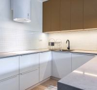 Konyha egy kétszobás lakásban fehér szekrényekkel, fekete csapteleppel és készülékekkel.