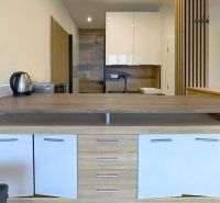 Konyha a Nyaraló apartmanban fa mintázatú padlóval és fa asztallal.