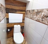 Rekreációs apartman WC-je dekoratív burkolatokkal és fa hatású padlóval.