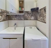 Fürdőszoba a nyaraló apartmanban mosógéppel és mintás csempékkel a falakon.