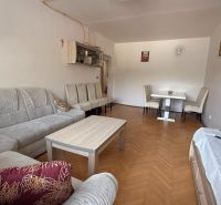 Nappali egy 4 szobás lakásban kényelmes ülőgarnitúrával és fa dekorációjú padlóval.