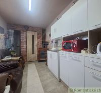 Konyha a házban fehér szekrényekkel, piros mikrohullámú sütővel és bőrkanapékkal.
