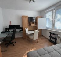 3 szobás lakás belső tere fa dekor padlóval, íróasztallal és kanapéval.