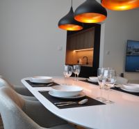 Étkezőasztal lámpákkal, előkészítve egy háromszobás lakásban, fa dekorációjú padlóval.