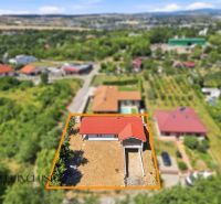 Családi ház a Nyitrai Mező utcában piros tetővel, zölddel körülvéve.