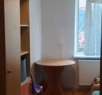 Egy szoba családi házban, fa dekorációjú padlóval, asztallal és polccal.