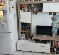 Nappali egy egyszobás lakásban fehér bútorokkal és dekorációkkal.