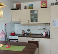 Konyha egy egyszobás lakásban, fa dekor padlóval és világos szekrényekkel.