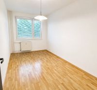 Üres szoba egy kétszobás lakásban, fa dekor padlóval és fehér falakkal.