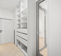 Folyosó beépített polcokkal és ajtókkal egy 4 szobás lakásban, fa dekor padlóval.