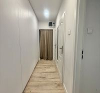 Fehér falú és fa dekorációjú padlójú folyosó egy háromszobás lakásban.