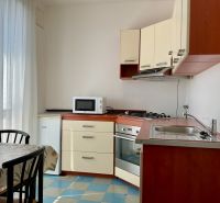 Konyha egy kétszobás lakásban mikrohullámú sütővel, tűzhellyel és étkezőasztallal.