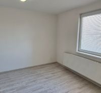 Szoba egy kétszobás lakásban fehér falakkal és fa dekorációjú padlóval.