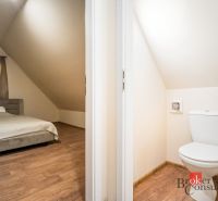 Hálószoba és WC fahatású padlóval rendelkező házikóban.