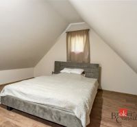 Tetőtéri hálószoba a házikóban, ággyal és fa dekorációjú padlóval.