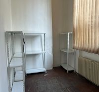 Iroda polcokkal, radiátorral és függönyökkel, fa dekoros padlóval.