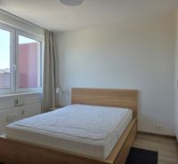 Hálószoba egy kétszobás lakásban ággyal és nagy ablakkal, fa dekoros padlóval.